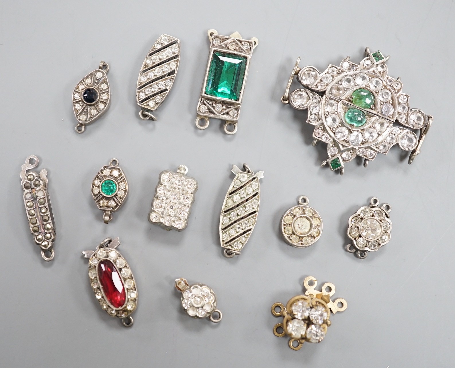 A small group of assorted white or base metal and paste set clasps.